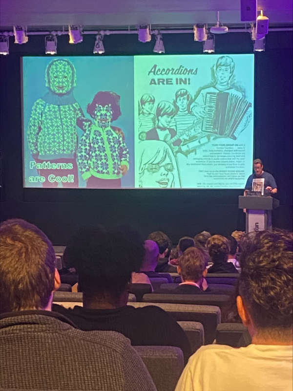 Ian Lloyd presenting at State of the Browser 2023. The slide on screen features two old adverts, one of them relating to patterns, the other accordions. The slide reads 'Patterns are cool!'